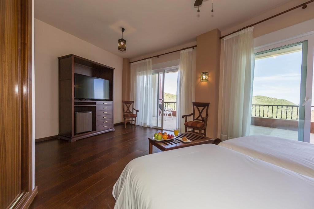 a bedroom with a bed and a television and a balcony at Hotel Wellness Marbella Hills in Ojén