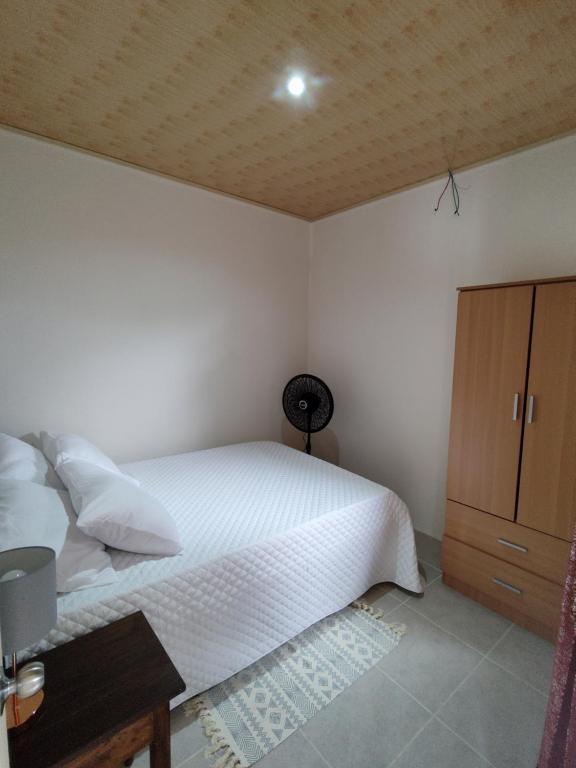 een slaapkamer met een wit bed en een houten kast bij Apartamentos La Paz in Liberia