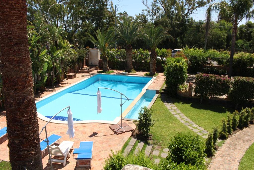una piscina en un patio con palmeras en The Green Seaside en Fondachello