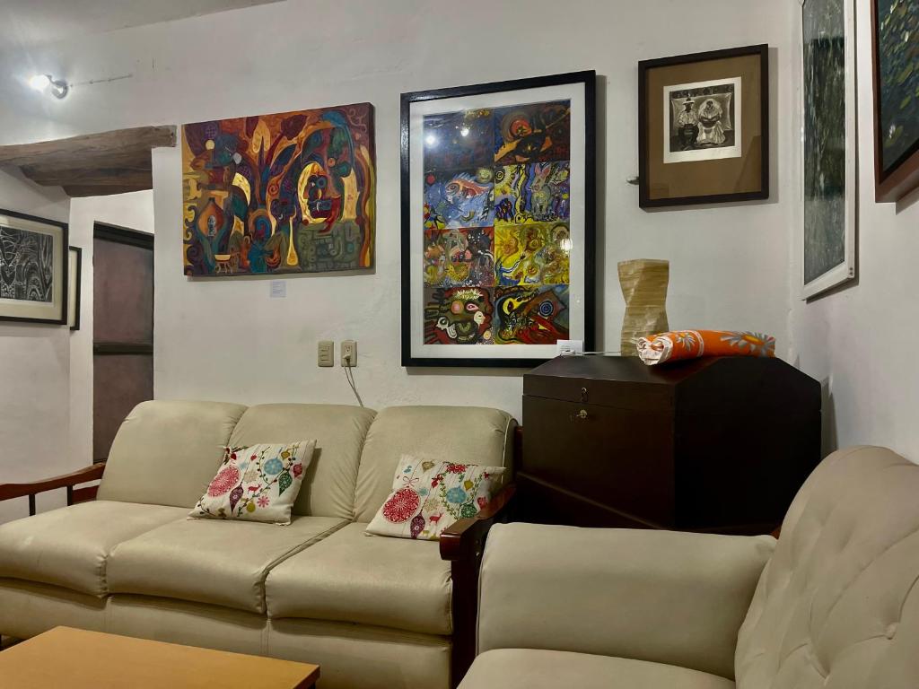 sala de estar con sofá y pinturas en la pared en Hotel casa teresa café galería, en Juchitán de Zaragoza