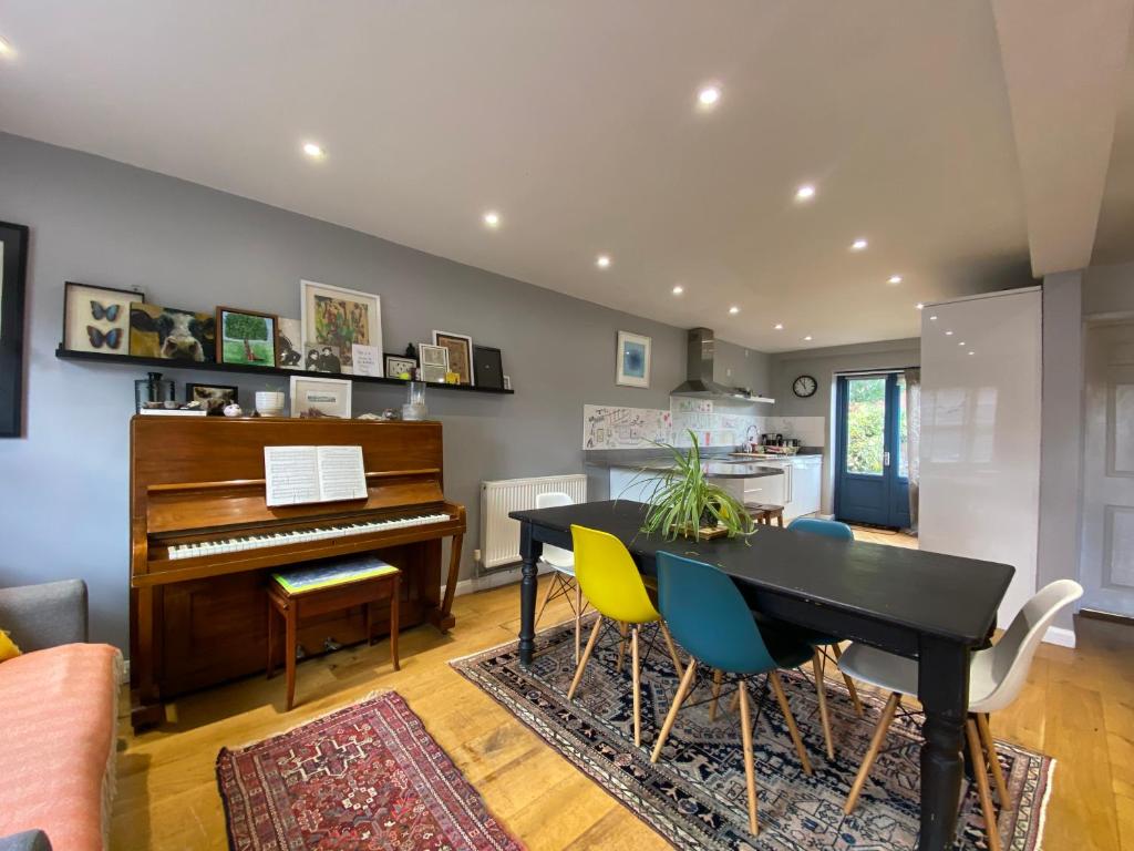 uma sala de estar com um piano, uma mesa e cadeiras em Artist's eclectic Town House close to river em Woodbridge