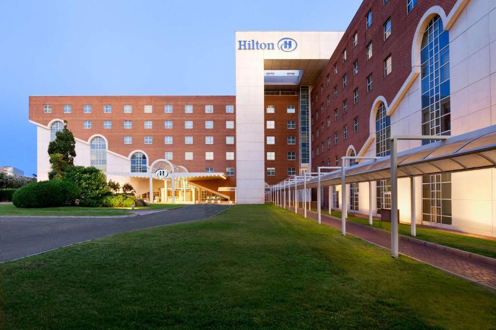 a large building with a green lawn in front of it at Hilton Rome Airport in Fiumicino