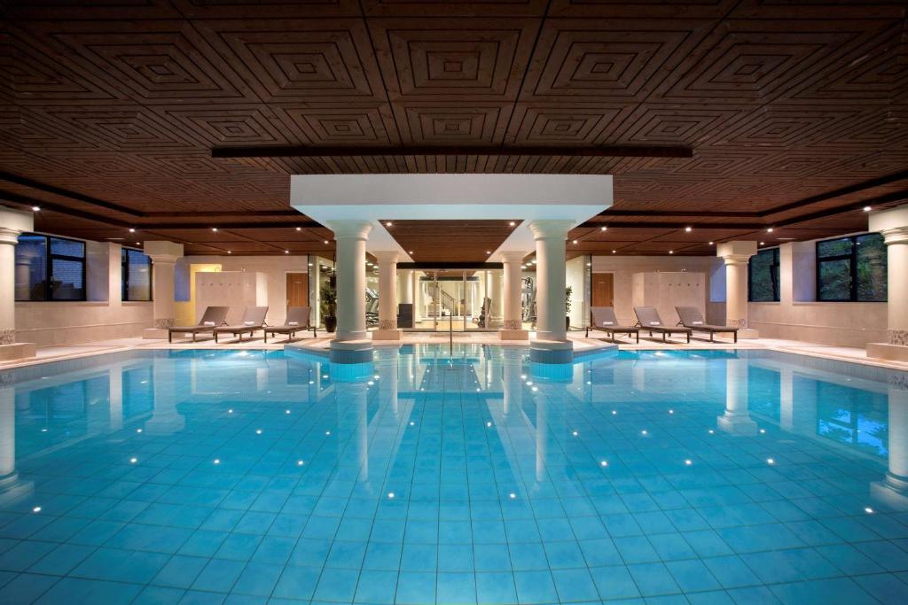 een groot zwembad met stoelen in een gebouw bij DoubleTree by Hilton Royal Parc Soestduinen in Soestduinen