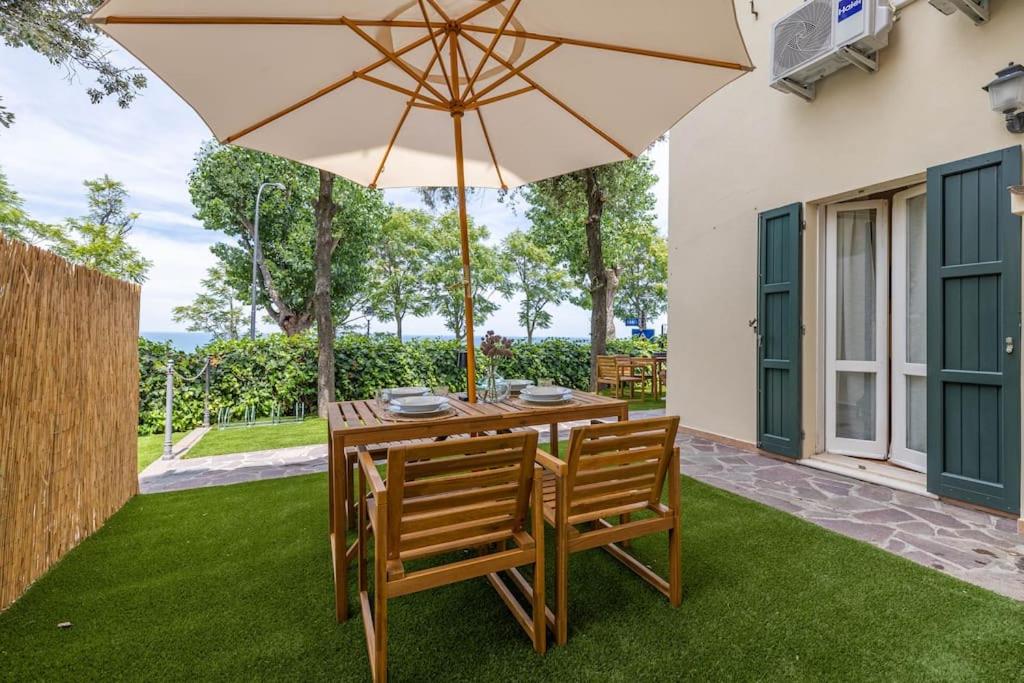 un tavolo in legno con due sedie e un ombrellone di Casa Orizzonte - Appartamento con vista a Gabicce Mare