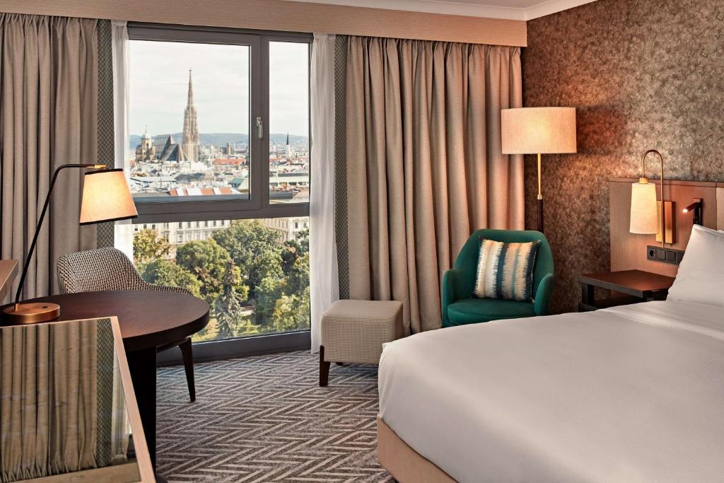 Pokój hotelowy z łóżkiem, biurkiem i oknem w obiekcie Hilton Vienna Park w Wiedniu