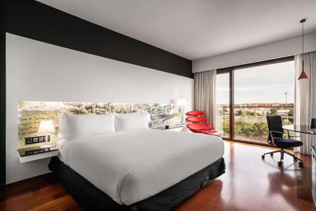 een slaapkamer met een groot bed en een groot raam bij Hilton Madrid Airport in Madrid