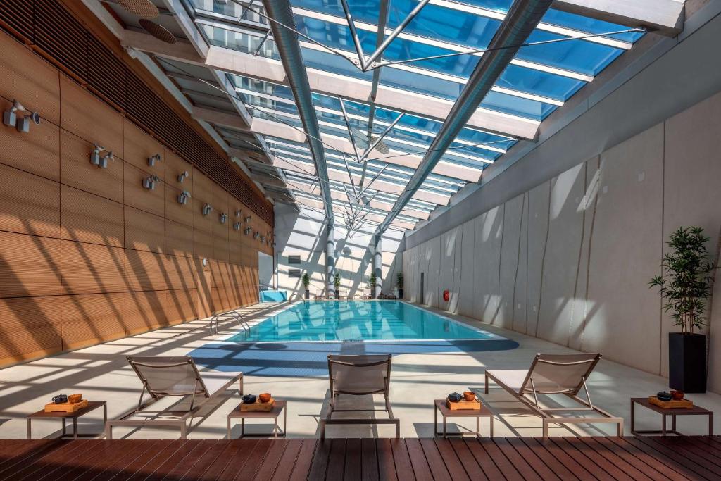 a swimming pool in a building with chairs and a ceiling at Hilton Geneva Hotel and Conference Centre in Geneva