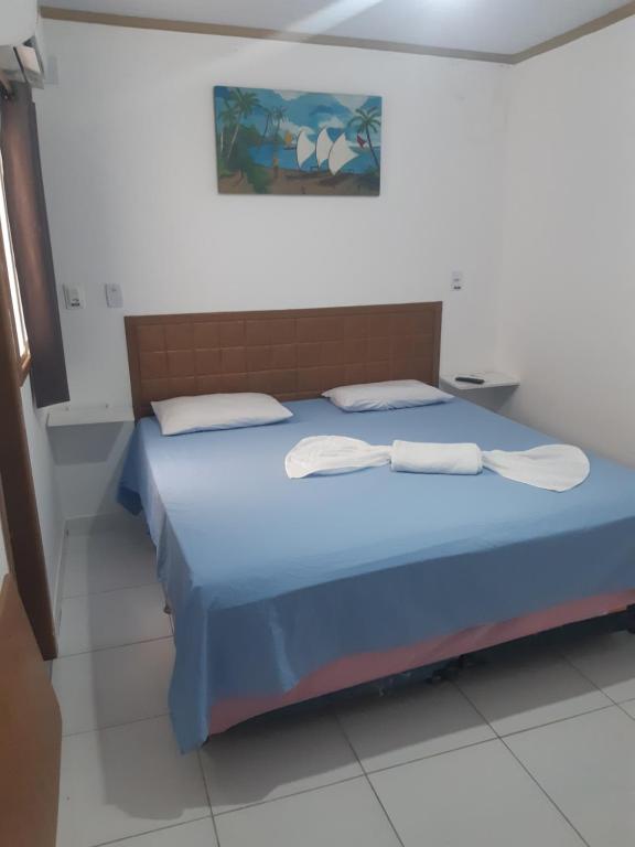 um quarto com uma cama azul com duas toalhas em Pousada 4 estações em Madre de Deus