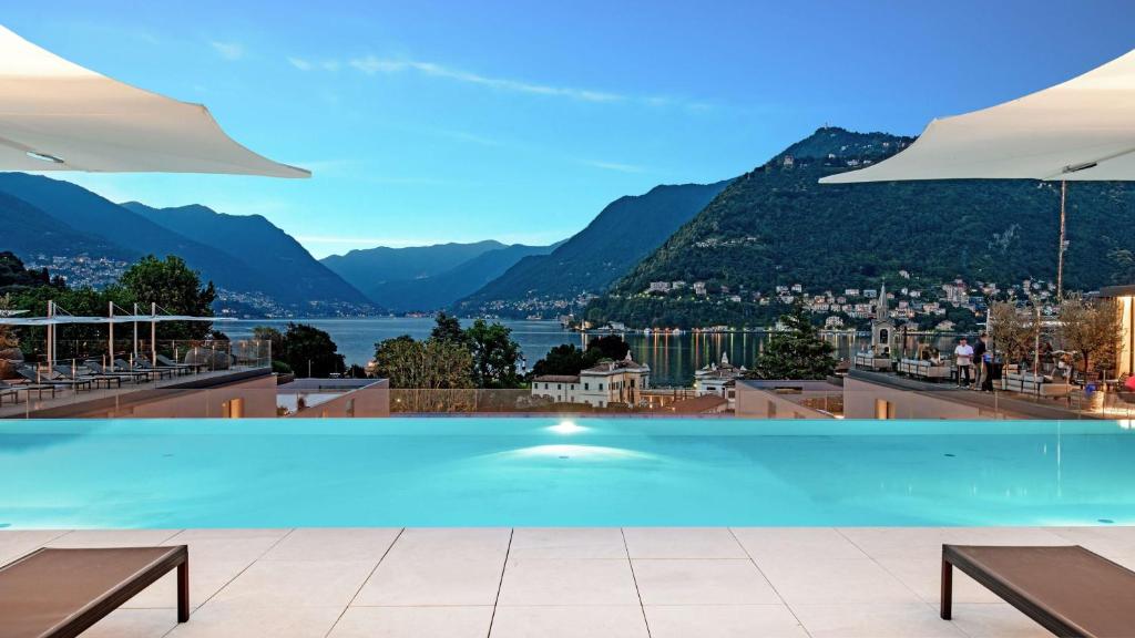 a swimming pool with a view of the mountains at Hilton Lake Como in Como