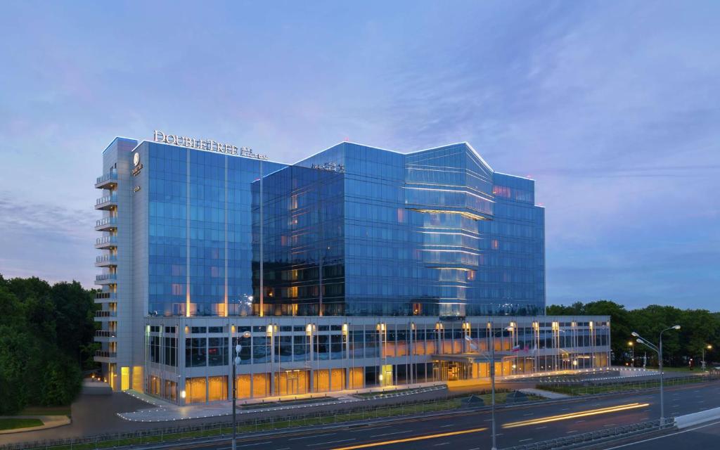 un gran edificio de oficinas de cristal con una calle delante en DoubleTree By Hilton Moscow - Vnukovo Airport Hotel, en Vnukovo
