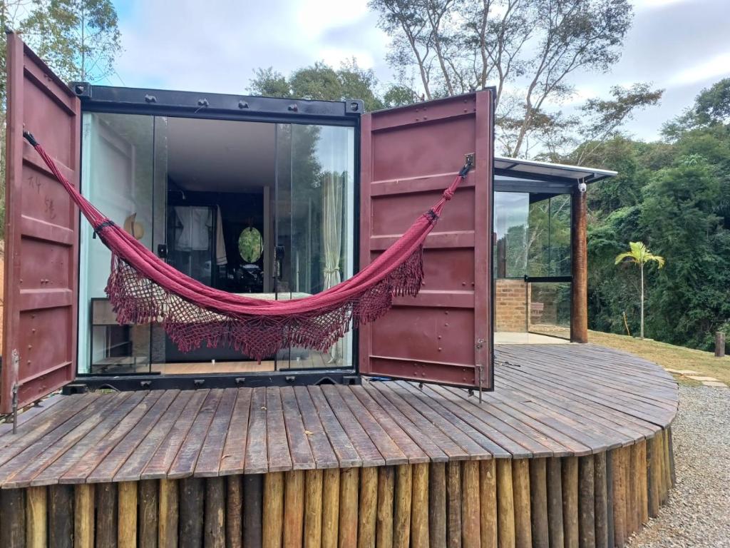 una casa con una hamaca en una terraza de madera en Casa Container, Vista para o Lago e integrada com a Natureza - Miguel Pereira, en Miguel Pereira