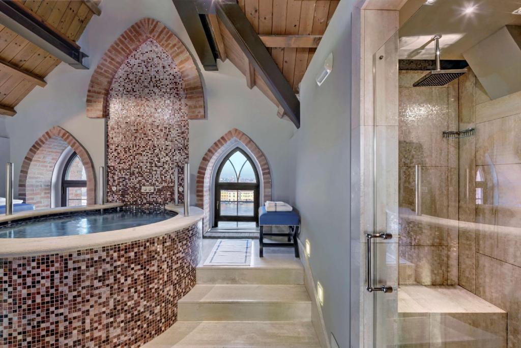 a bathroom with a tub and a walk in shower at Hilton Molino Stucky Venice in Venice