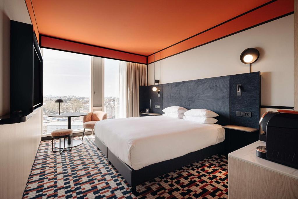 Cette chambre comprend un grand lit et une télévision. dans l'établissement DoubleTree by Hilton Amsterdam Centraal Station, à Amsterdam