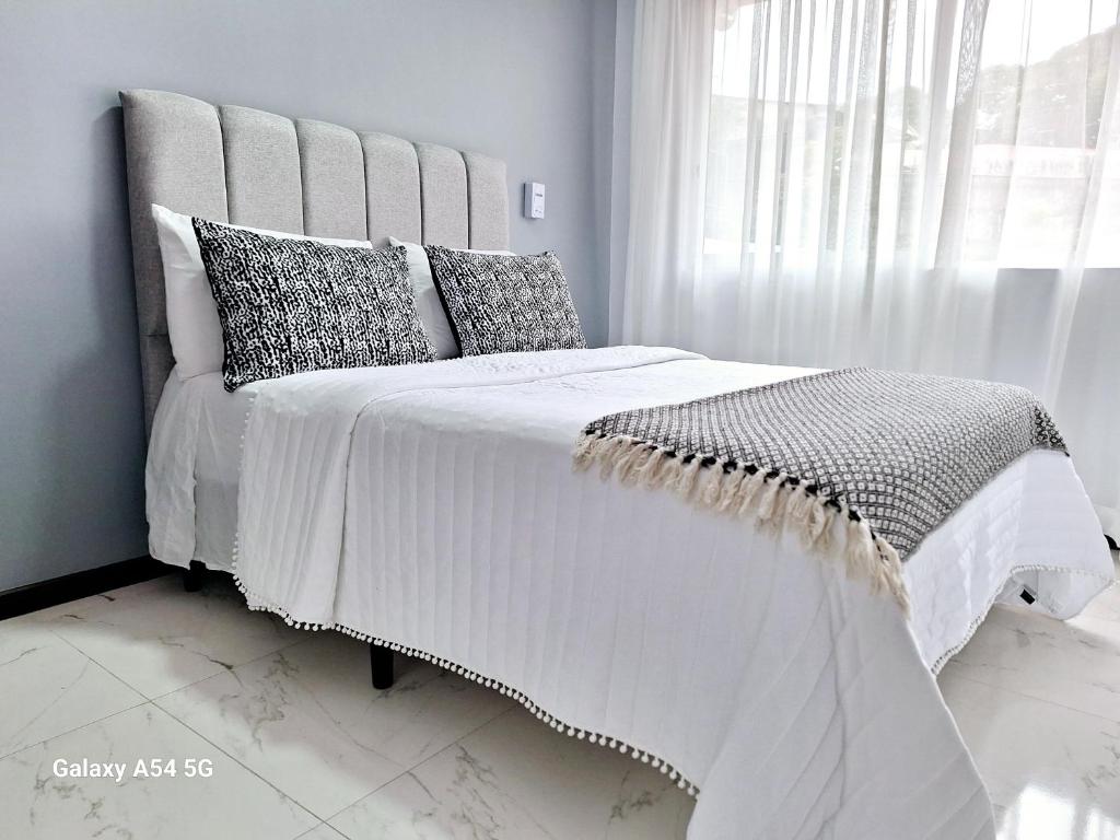 a bedroom with a white bed with pillows and a window at Casa Victoria Hostel in San Isidro