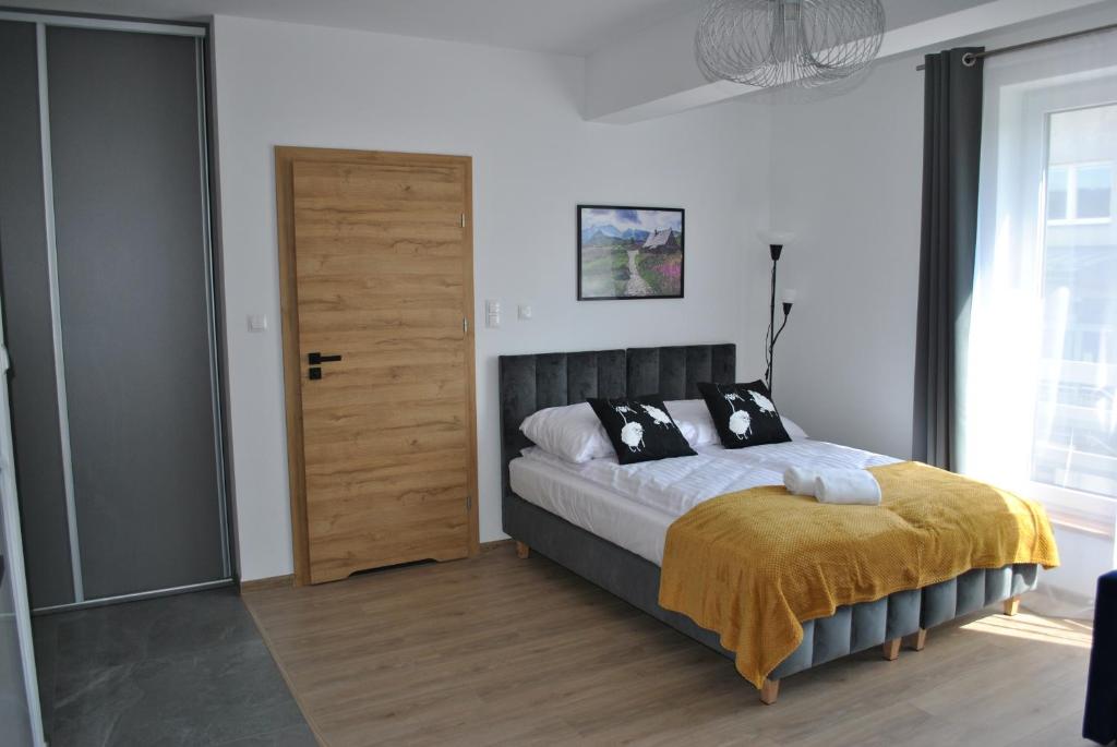 a bedroom with a bed and a wooden door at Apart4You Apartamenty Nowy Targ in Nowy Targ