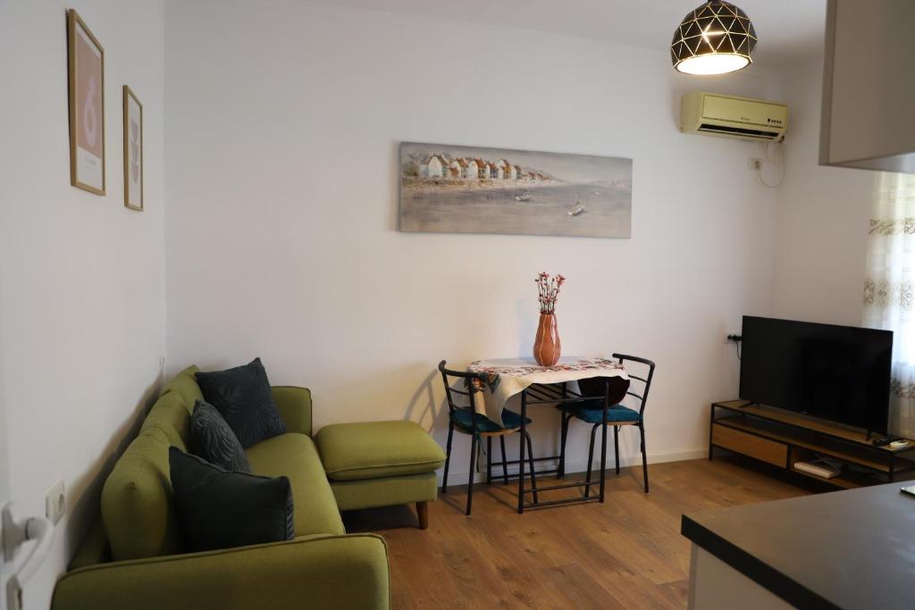 ein Wohnzimmer mit einem grünen Sofa und einem Tisch in der Unterkunft Daniel City Center Apartment in Berat