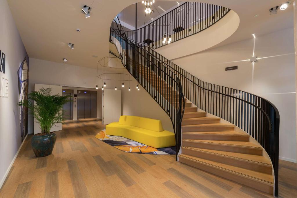 a staircase with a yellow couch in a living room at Hampton By Hilton Antwerp Central Station in Antwerp