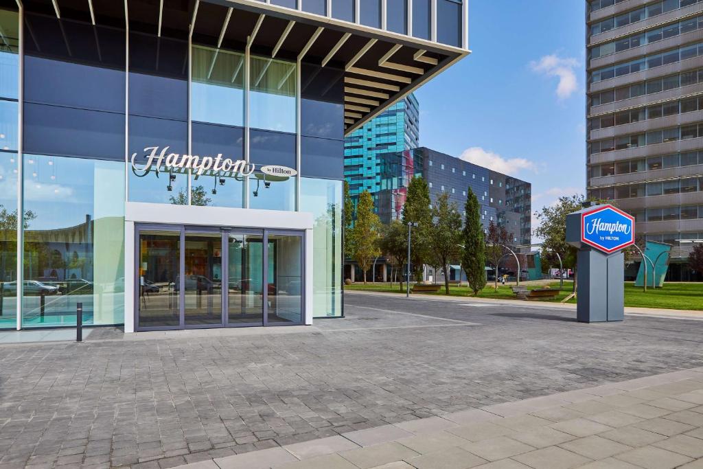 a building with a pharmacy sign in front of it at Hampton By Hilton Barcelona Fira Gran Via in Hospitalet de Llobregat