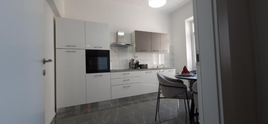 a kitchen with white cabinets and a small table at MC Centar Apartman in Pula