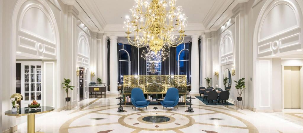 a lobby with a chandelier and a table and chairs at Hilton Brussels Grand Place in Brussels