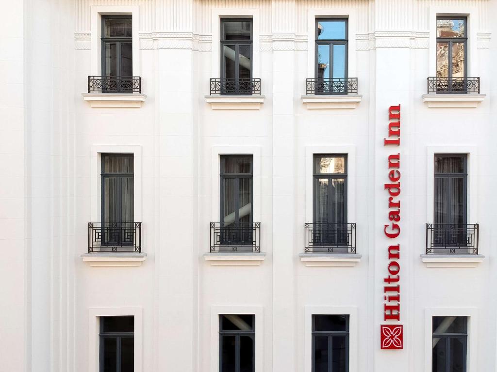 a white building with a red hotel sign on it at Hilton Garden Inn Bucharest Old Town in Bucharest