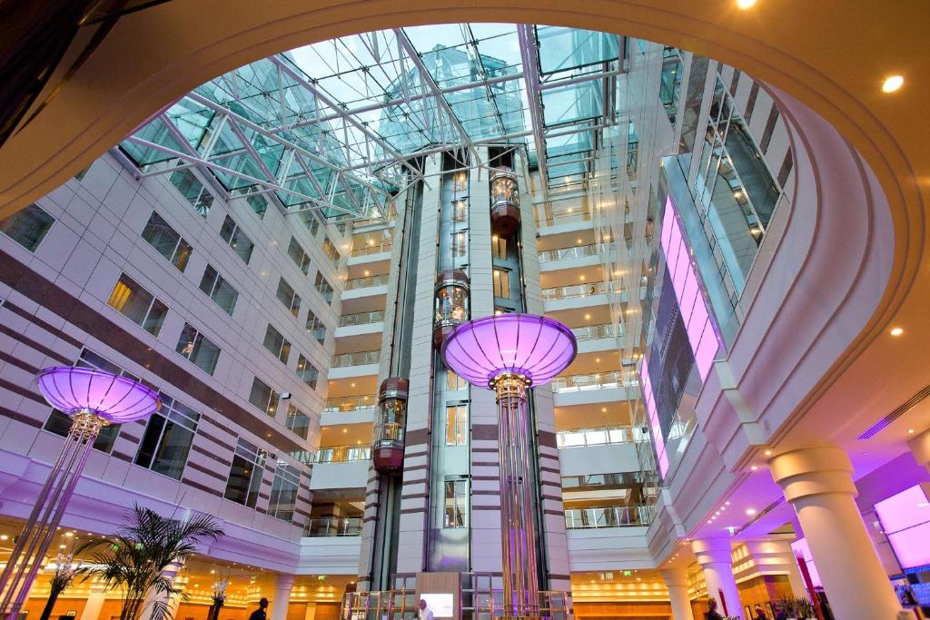 a large building with glass ceilings and purple lights at Hilton Paris Charles De Gaulle Airport in Roissy-en-France