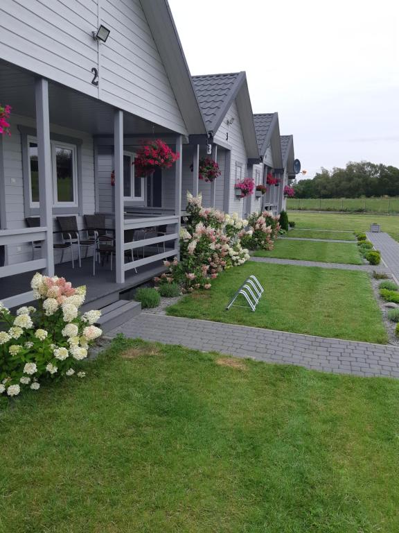 a row of houses on a lawn with flowers at Bajkowe Chatki in Rusinowo