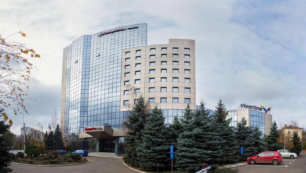 un grand bâtiment avec une voiture garée devant lui dans l'établissement Hampton By Hilton Iasi, à Iaşi