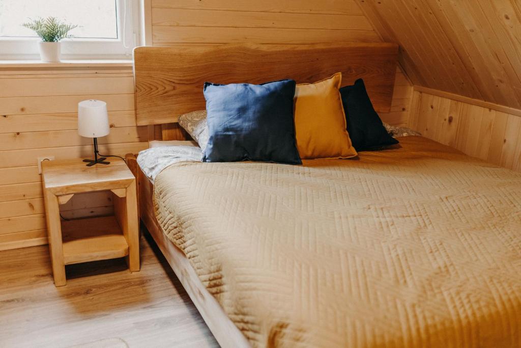 uma cama com almofadas azuis e amarelas num quarto em Domek na skarpie em Joniec