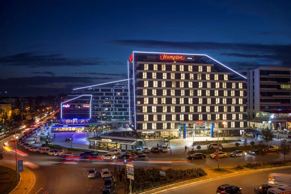 a building with a sign on the side of it at night at Hampton by Hilton Istanbul Kurtkoy in Istanbul