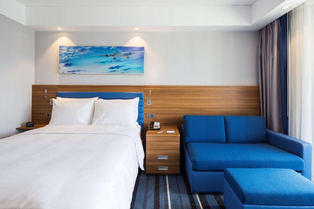 a hotel room with a bed and a blue chair at Hampton by Hilton Istanbul Kurtkoy in Istanbul