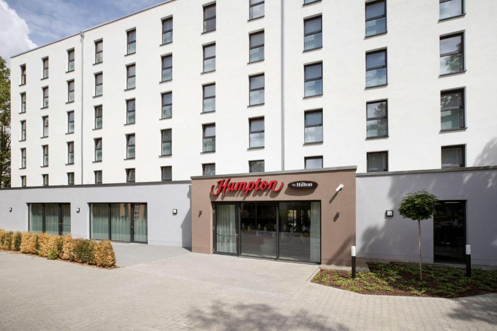 ein weißes Gebäude mit einem Schild für Hampton Inn in der Unterkunft Hampton By Hilton Kaiserslautern in Kaiserslautern