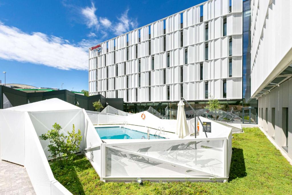 um hotel com piscina em frente a um edifício em Hampton By Hilton Alcobendas Madrid em Alcobendas