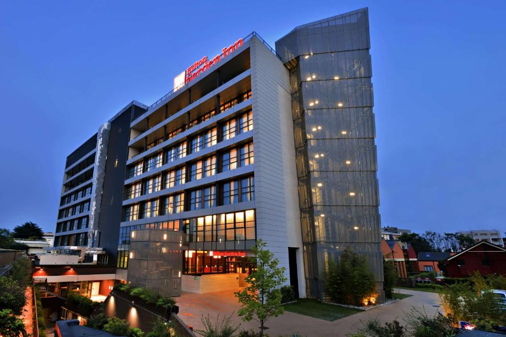 a large building with lights on the side of it at Hilton Garden Inn Milan North in Milan