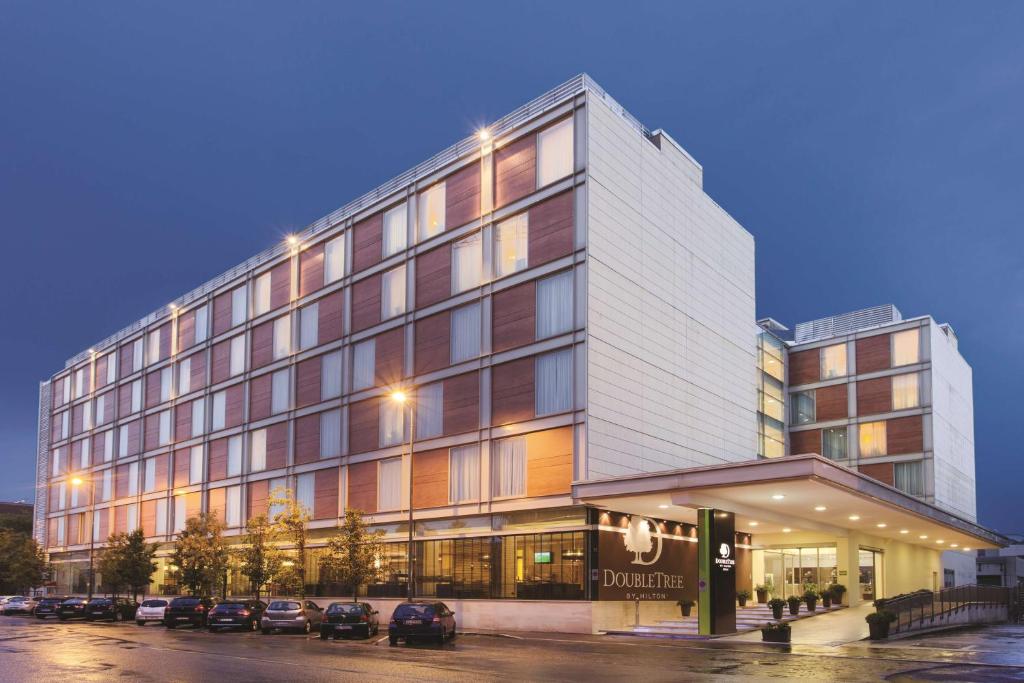 un gran edificio con coches estacionados frente a él en DoubleTree By Hilton Milan, en Milán