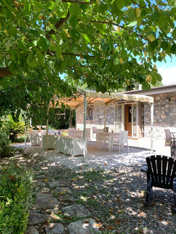 un patio con mesa y sillas bajo un árbol en I Suoni di Valle Martina en Poderia