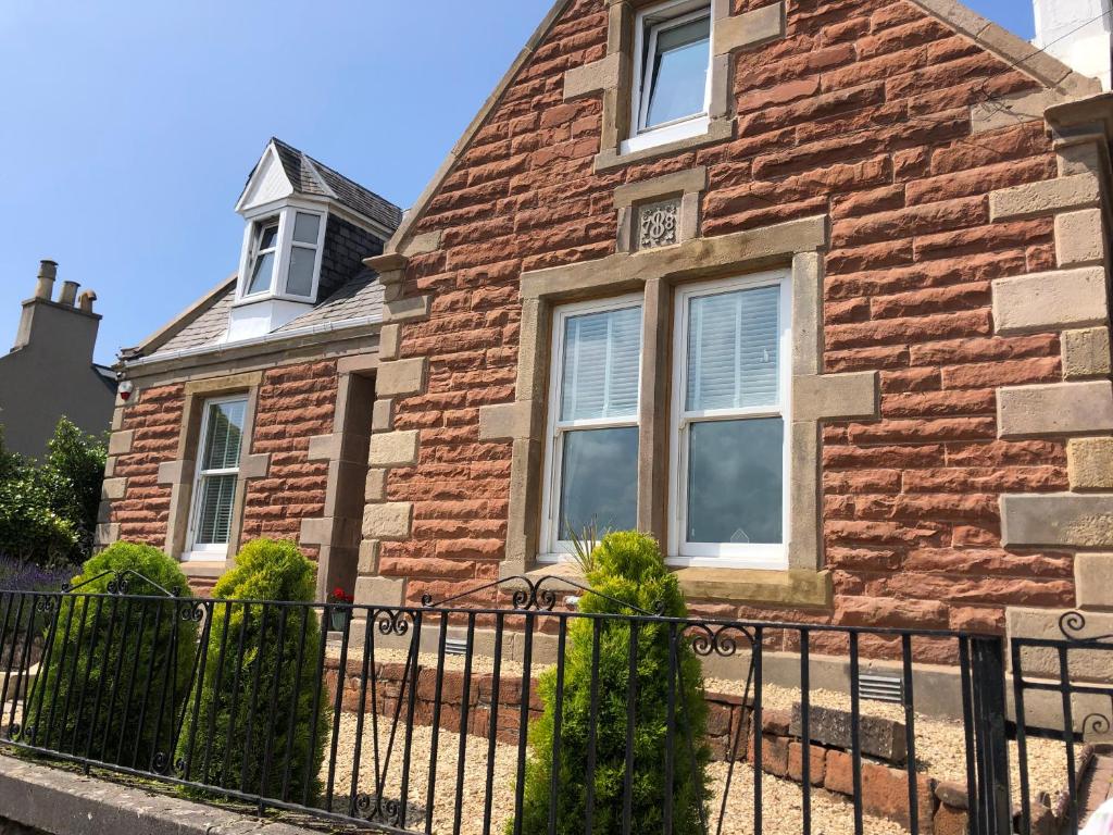 a brick house with a fence in front of it at Hetherington House in Maybole