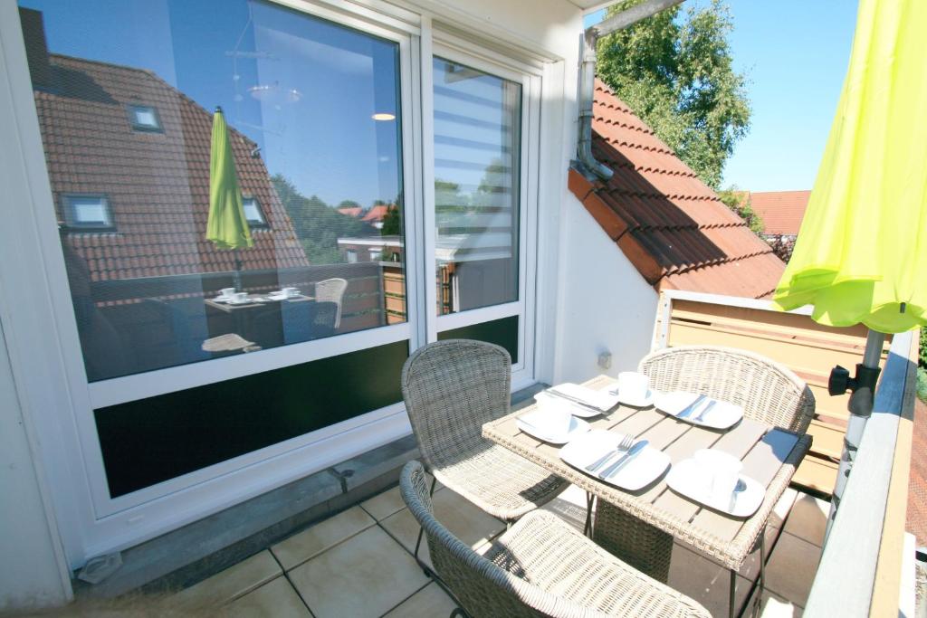 patio con mesa y sillas en el balcón en Ferienwohnung Muschelweg 9b Ostermann, en Norddeich