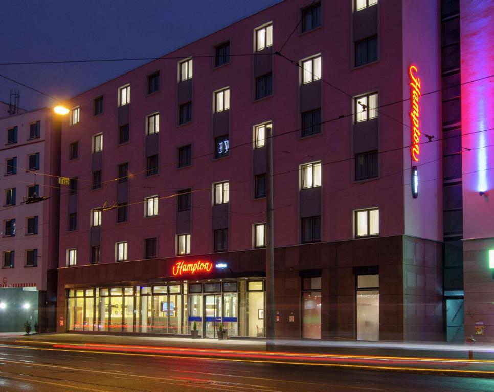 ein Gebäude mit einem Neonschild davor in der Unterkunft Hampton by Hilton Nürnberg City Center in Nürnberg