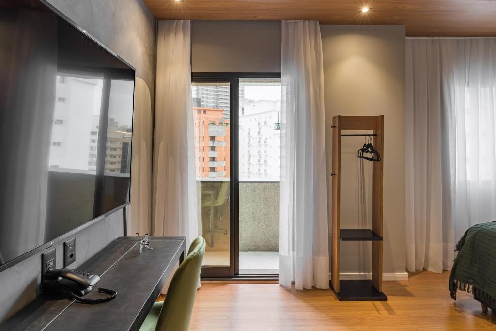 a room with a desk and a bed and a window at Cyclinn Jesuíno Arruda Itaim in São Paulo