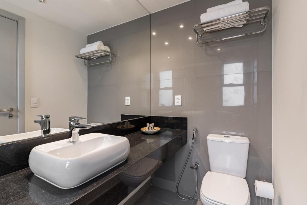 a bathroom with a white toilet and a sink at Cyclinn Jesuíno Arruda Itaim in São Paulo