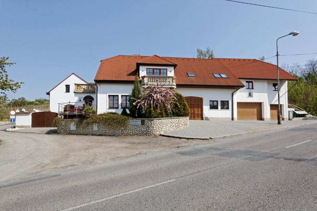 a white house with a red roof on a street at Apartmány Turold Mikulov in Mikulov