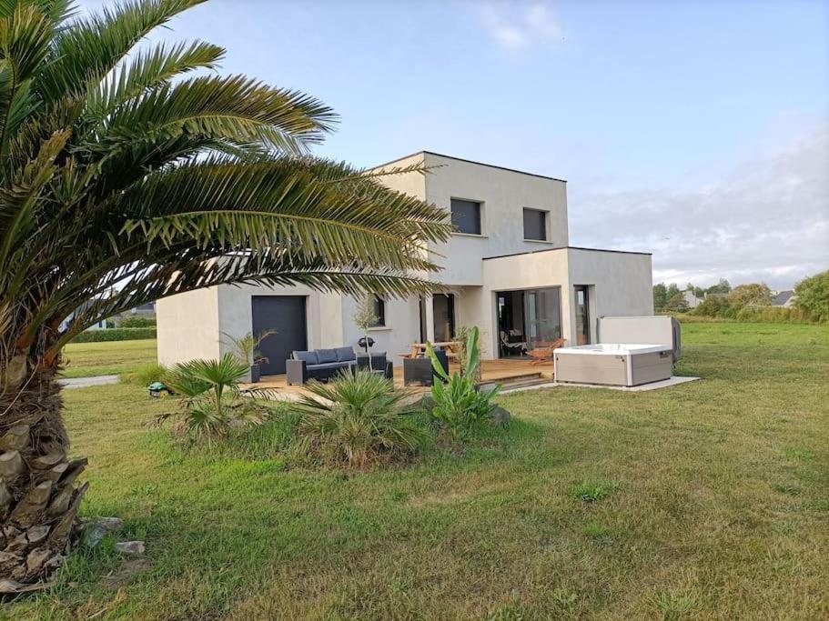 une maison blanche avec un palmier dans un champ dans l'établissement Maison de vacances Ty Zoizos à 250 m de la plage, à Plouescat