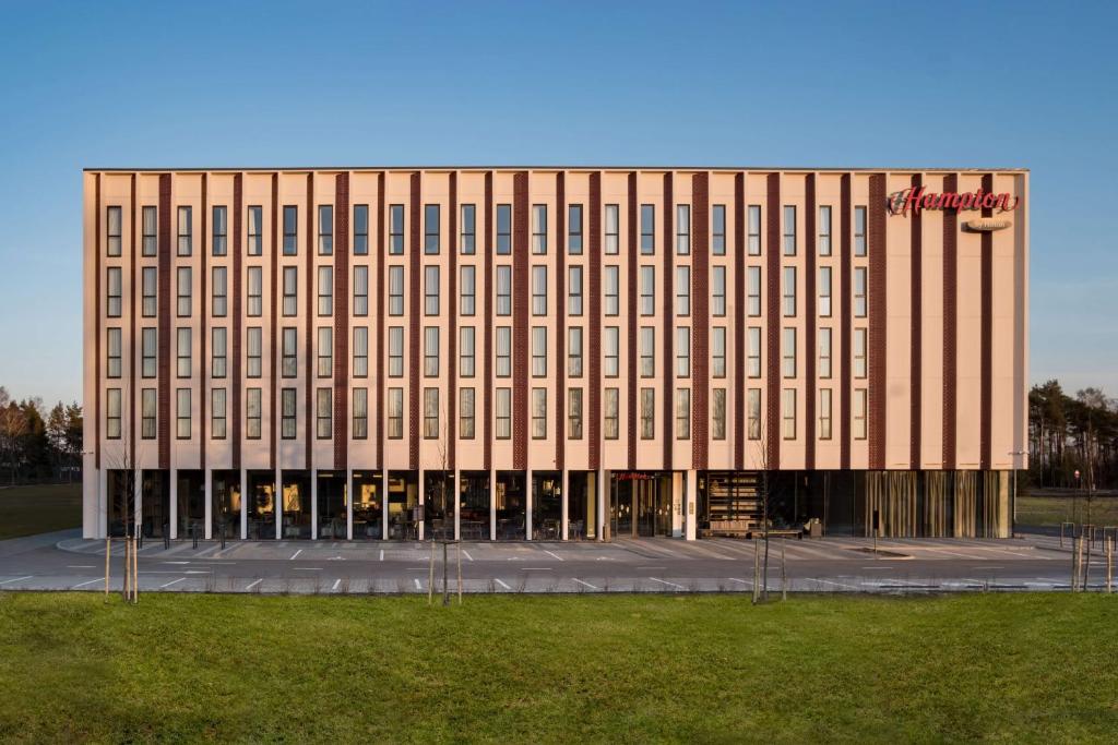 a large building with a sign on the front of it at Hampton by Hilton Riga Airport in Rīga