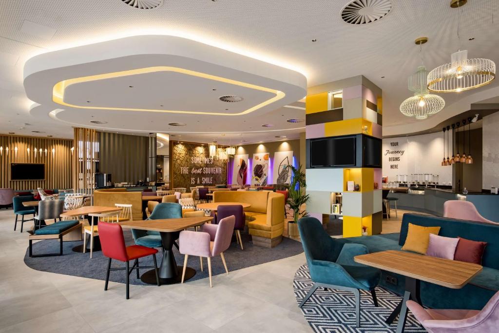 a restaurant with tables and chairs and a bar at Hampton by Hilton Riga Airport in Rīga