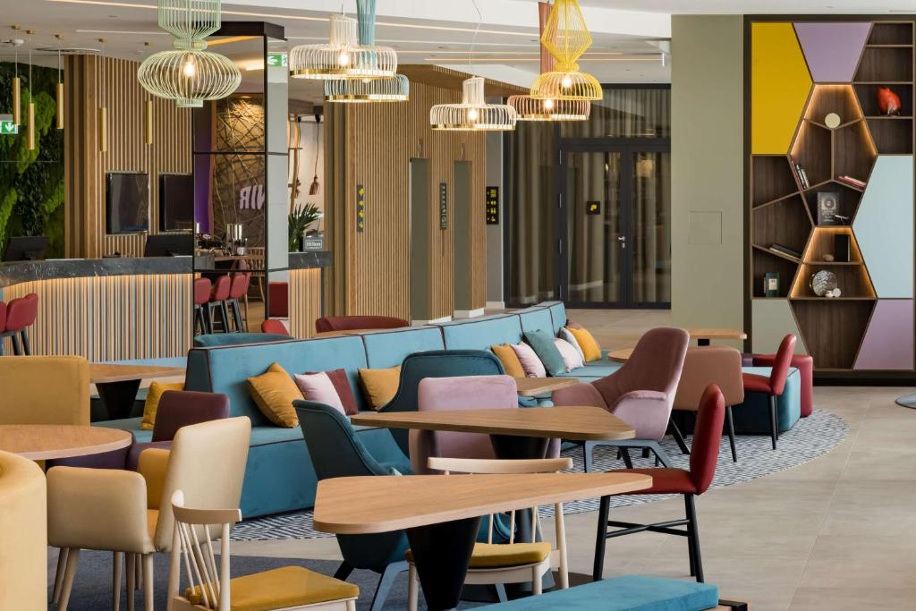 a lobby with tables and chairs and chandeliers at Hampton by Hilton Riga Airport in Riga