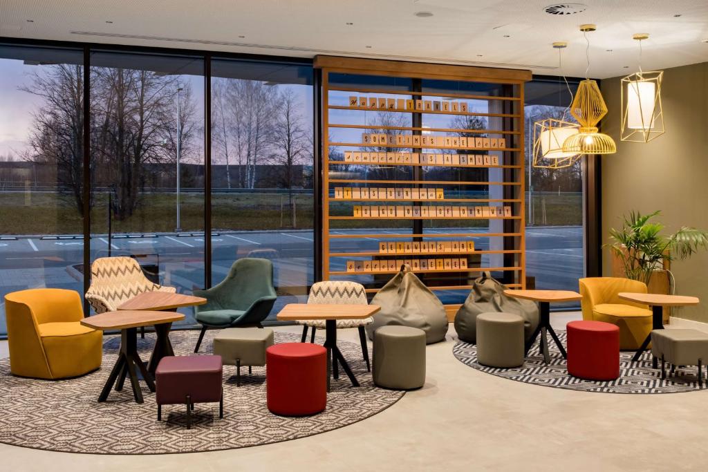 a library with tables and chairs and windows at Hampton by Hilton Riga Airport in Riga