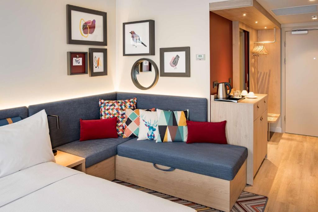 a room with a blue couch with colorful pillows at Hampton by Hilton Riga Airport in Riga