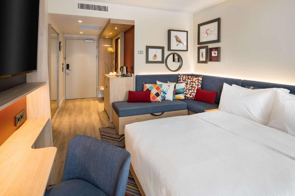 a hotel room with a bed and a couch at Hampton by Hilton Riga Airport in Riga