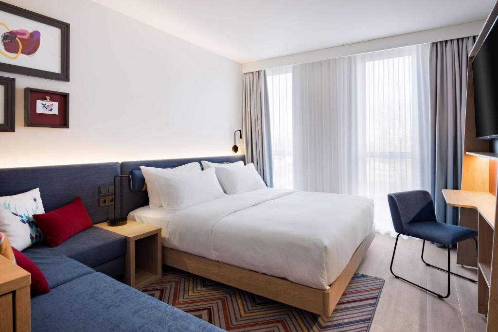 a hotel room with a bed and a couch at Hampton by Hilton Riga Airport in Riga